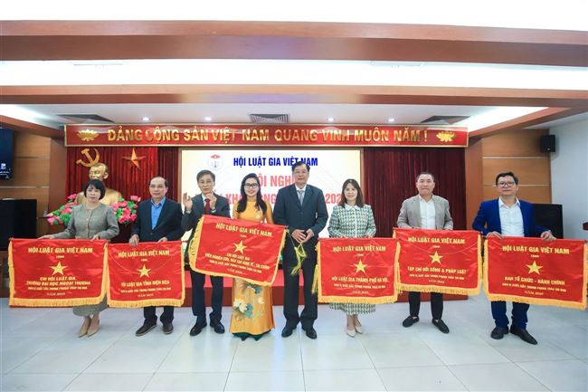 Bà Nguyễn Thị Mai Hoa - Đại diện Chi hội Luật gia Viện Nghiên cứu, đào tạo, kinh tế - tài chính lên nhận Cờ thi đua của Hội Luật gia Việt Nam